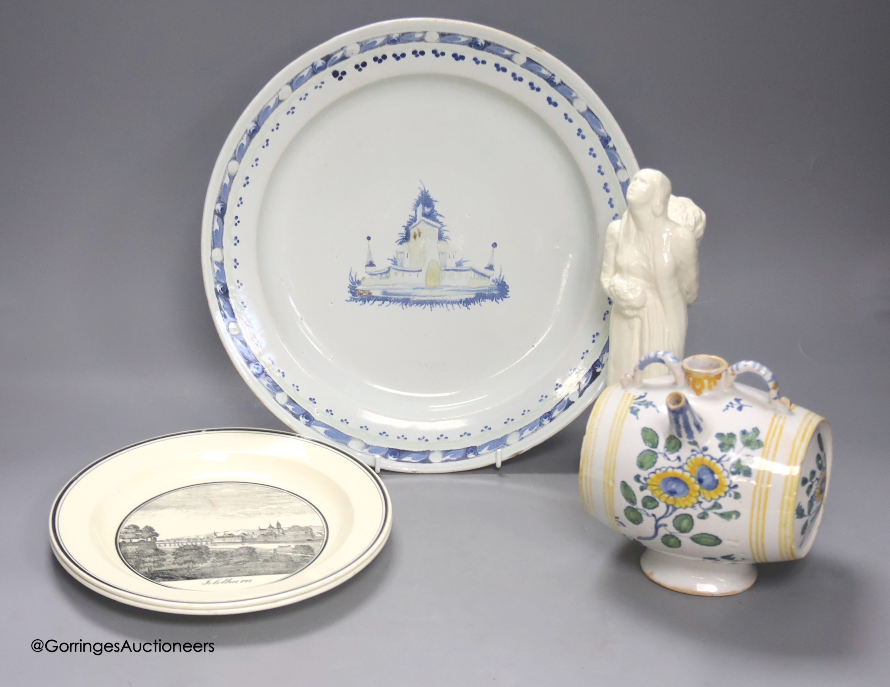 A Continental tin glaze dish, 18th/19th century, possibly Portuguese, a faience Gin barrel, a pottery figure, inscribed in pencil ‘I Barry’ and two Zell Creamware topographical plates